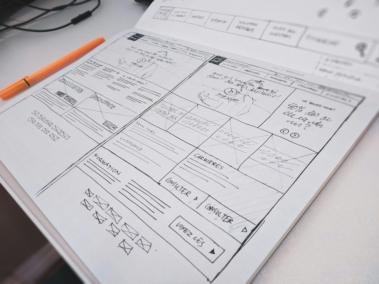 Hand-drawn website wireframe on paper with a pen