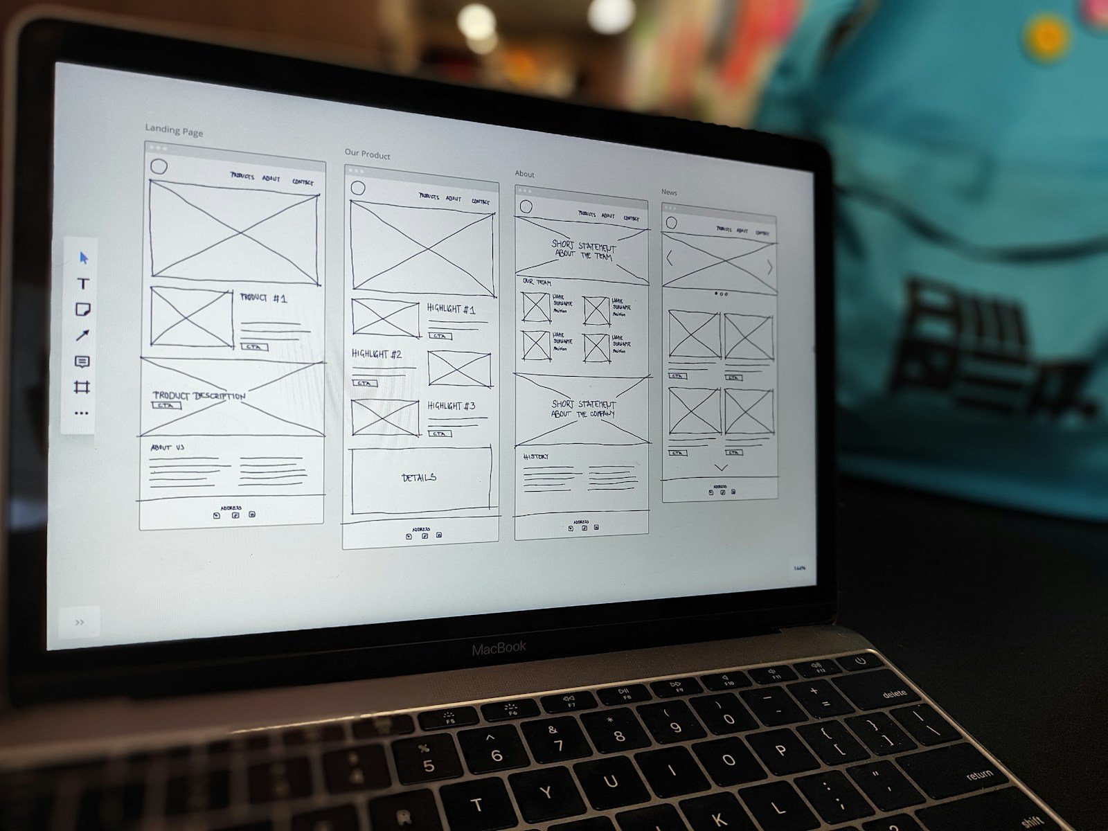 MacBook showing a website wireframe on an office desk