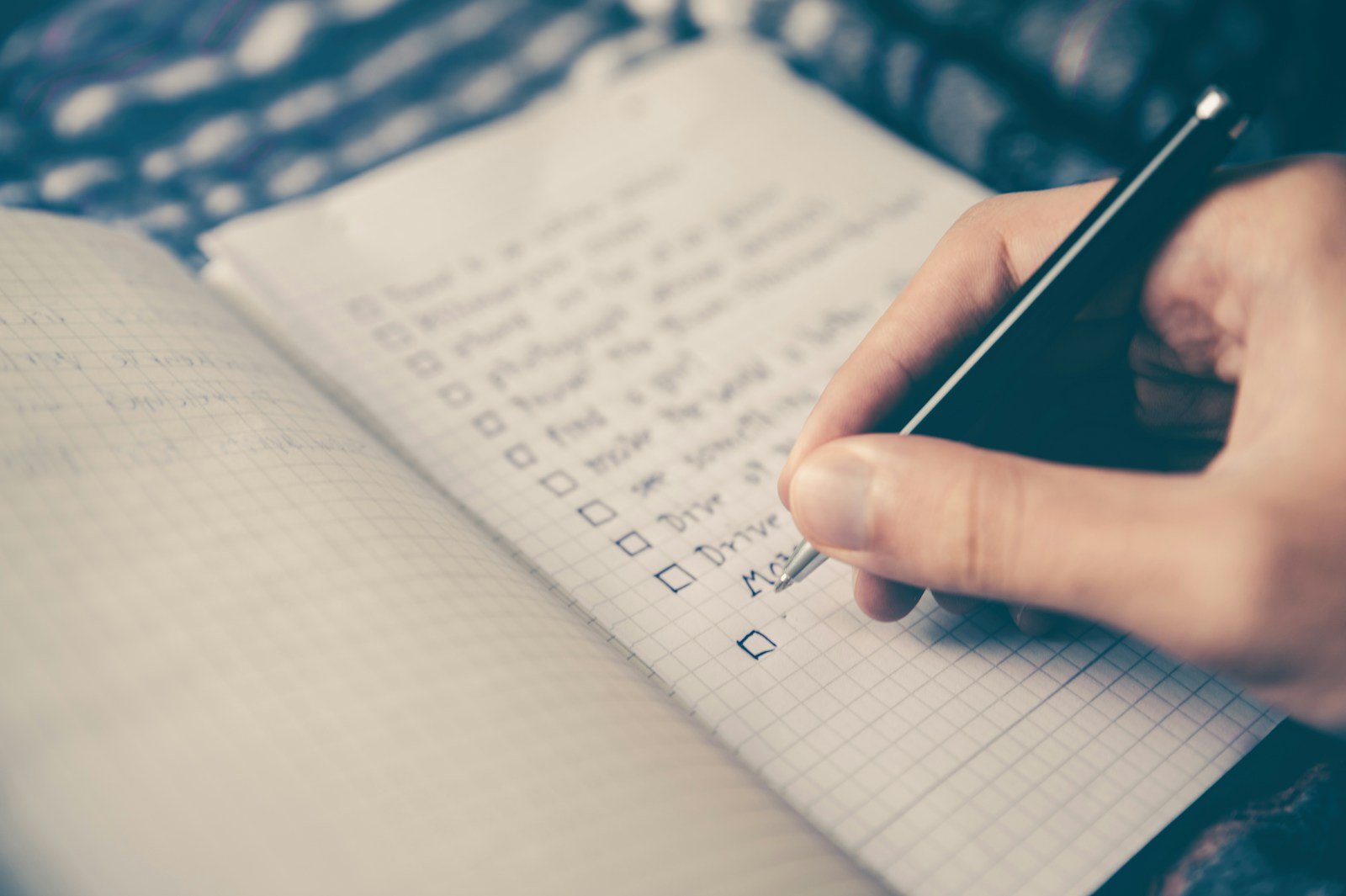 Laptop open to a notebook checklist with a pen
