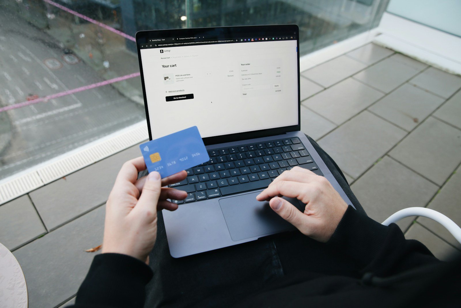 Person holding a card while completing an online purchase on a laptop