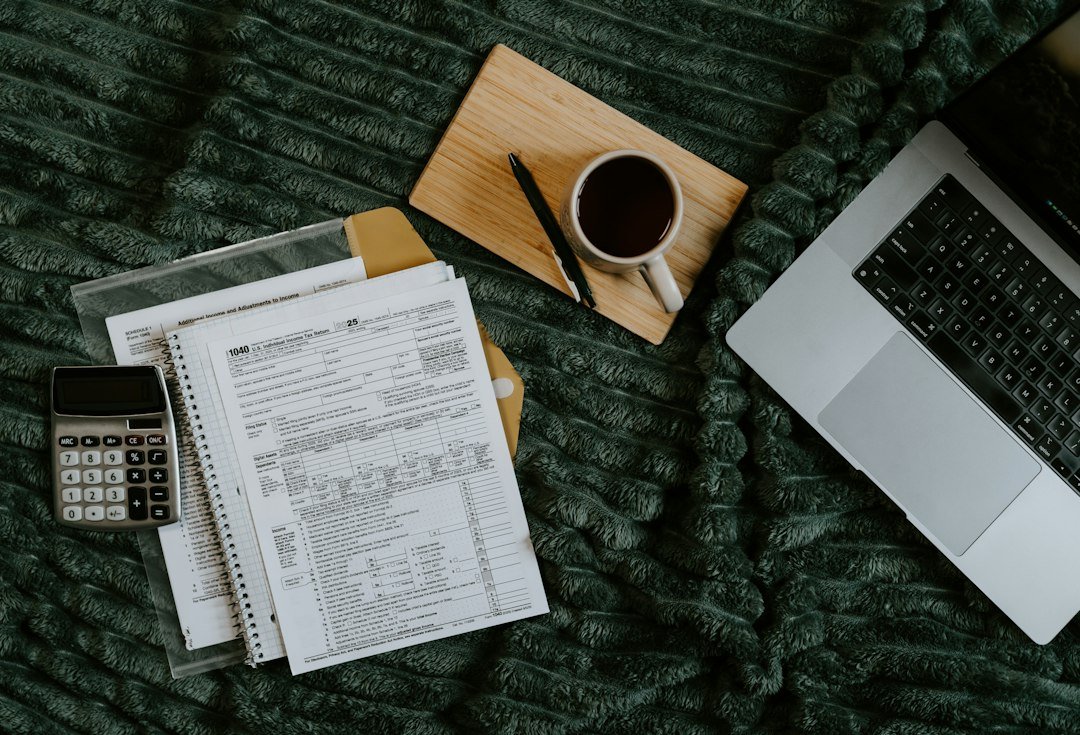 Laptop, papers, calculator and coffee while adding up yearly WordPress costs